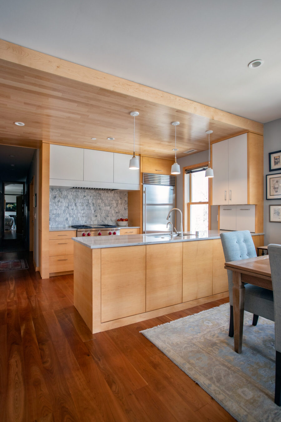 Chic, modern Twin Cities kitchen remodel integrates light cabinetry, warm woods, marble backsplash.