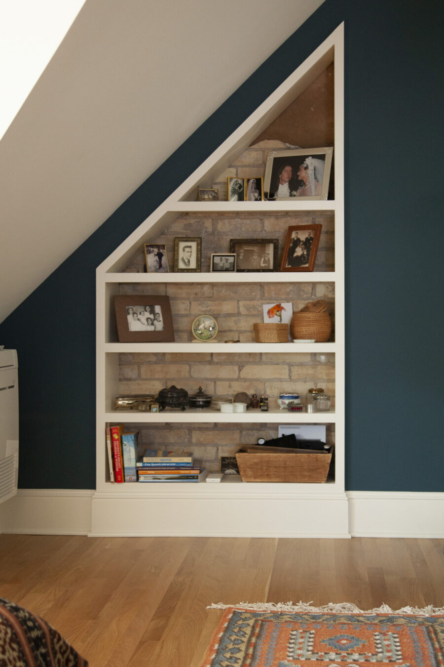 White-trimmed custom brick-backed shelving, teal wall, hardwood flooring. Twin Cities remodeling.