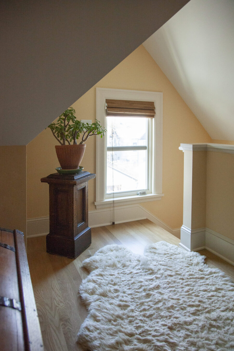 Twin Cities attic renovation brightens with natural light. It has light wood floors, pale yellow walls, and fluffy rug.