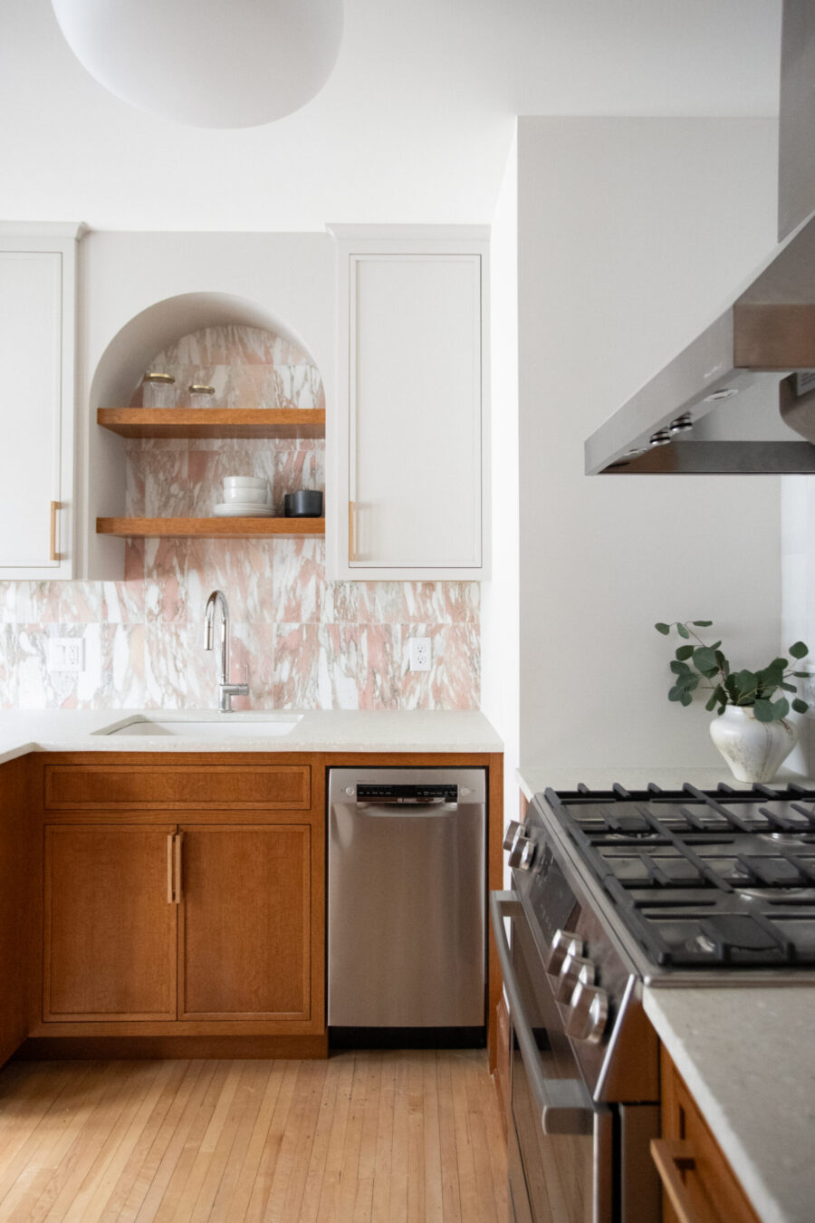 Twin Cities kitchen remodel highlights arched pink marble backsplash, wood cabinetry.