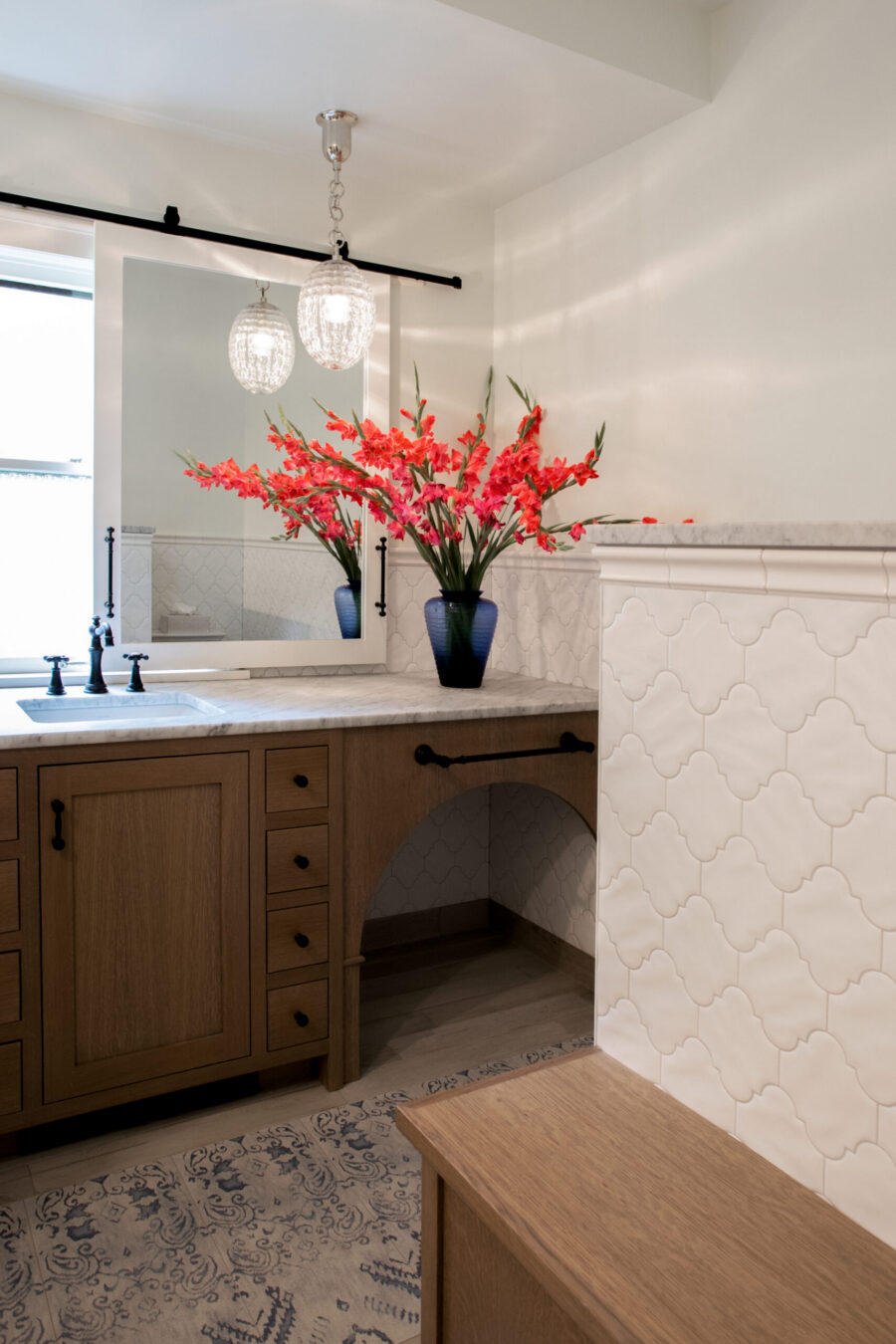Luxurious handcrafted bathroom cabinetry, marble countertop, unique scalloped wall tiles, pendant lighting.