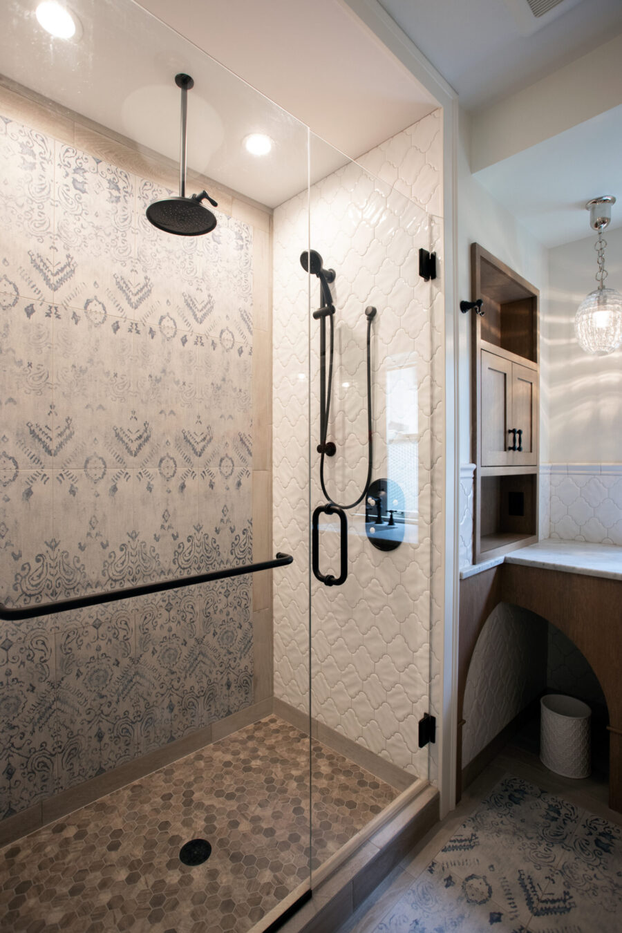 Twin Cities bathroom remodel: patterned tile shower, glass enclosure, black fixtures, warm vanity.