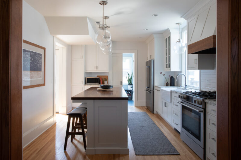 Bright Twin Cities kitchen remodel with white wall cabinets, dark wood island, stainless steel appliances.