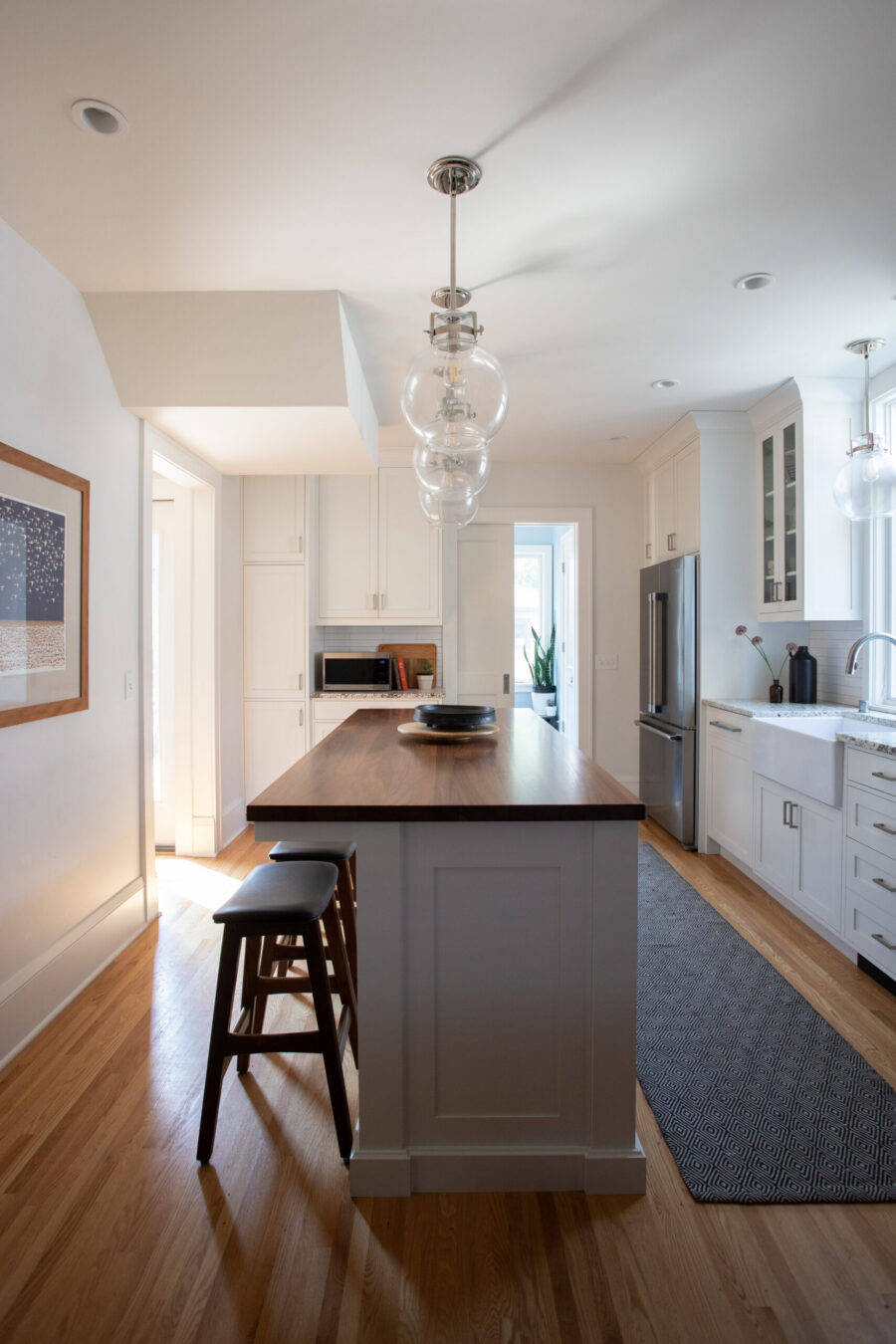 Modern Twin Cities kitchen renovation integrates white cabinetry, dark island, and polished hardwood flooring.