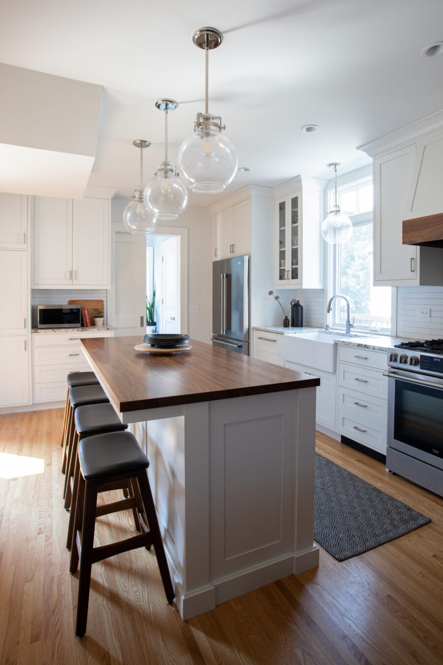 Bright Twin Cities kitchen remodel illuminates white cabinetry, dark island, hardwood flooring.
