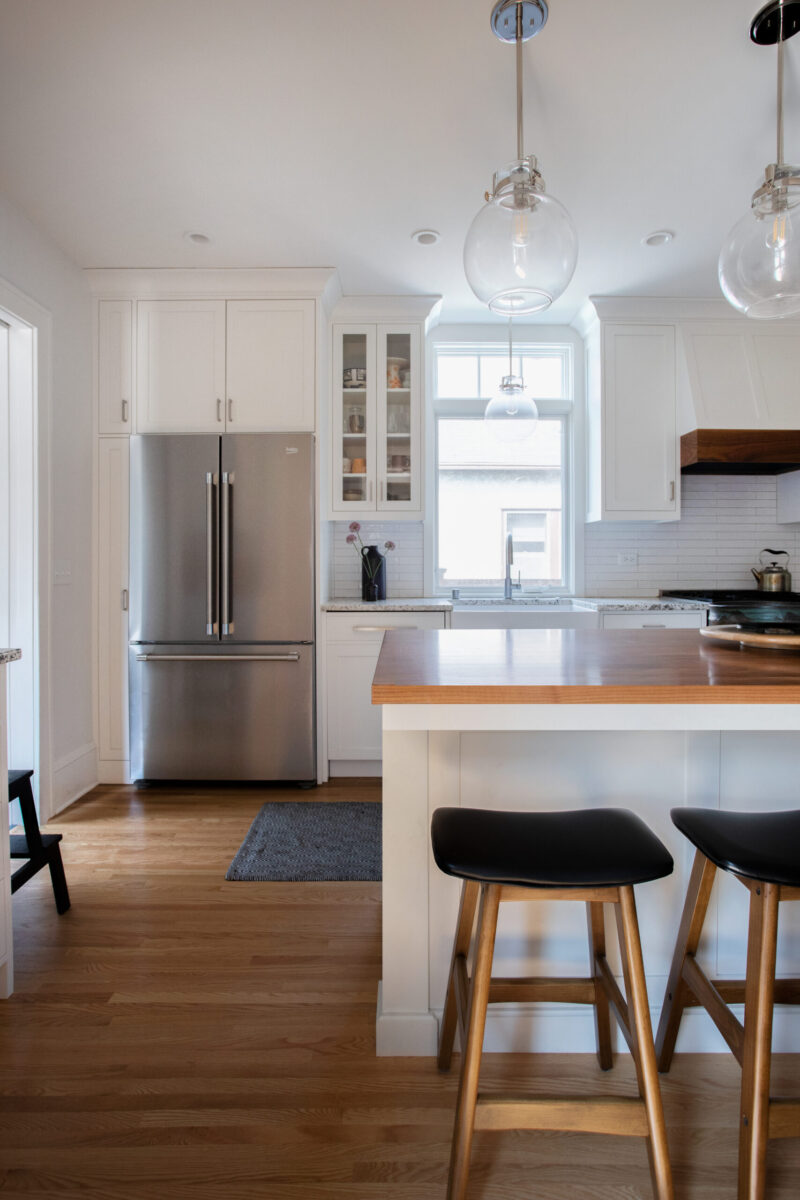 Renovated Twin Cities kitchen features expansive white cabinetry, stainless appliances, warm hardwood.