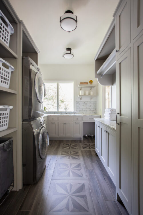 Natural light floods spacious-laundry-room with stacked washer-dryer and shaker-cabinetry