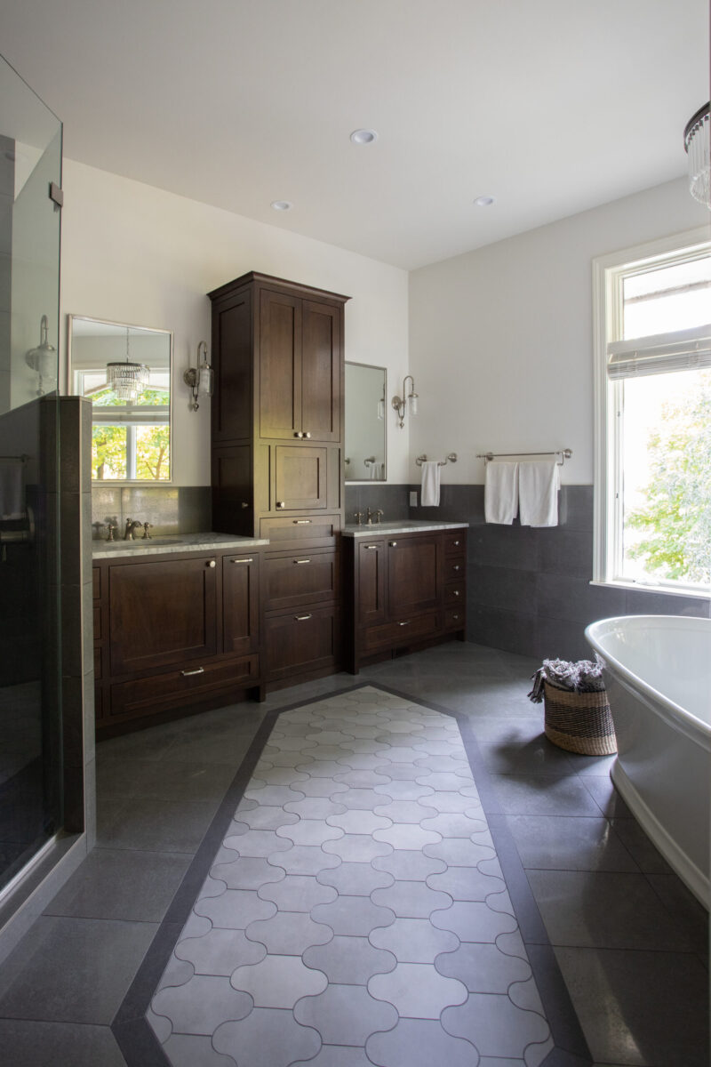 Twin Cities bathroom renovation offers dark wood cabinetry, patterned floor, freestanding tub.