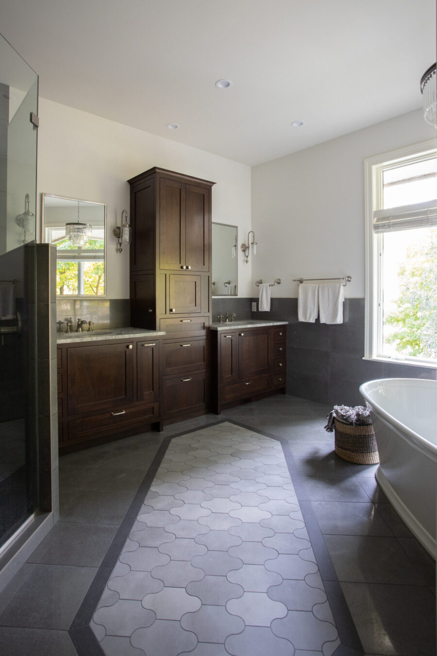 Twin Cities bathroom renovation offers dark wood cabinetry, patterned floor, freestanding tub.