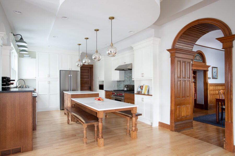Twin Cities kitchen renovation features bright white and wood cabinetry, stainless appliances, pendant lighting, and an arched wood doorway.