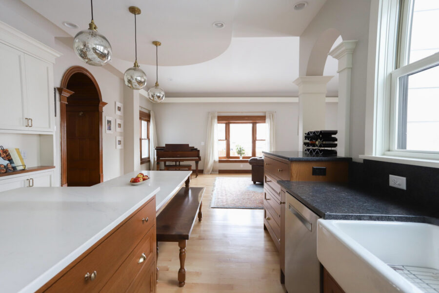 Bright Twin Cities kitchen remodel features an open-concept design, light wood floors, white and wood cabinets, pendant lights.