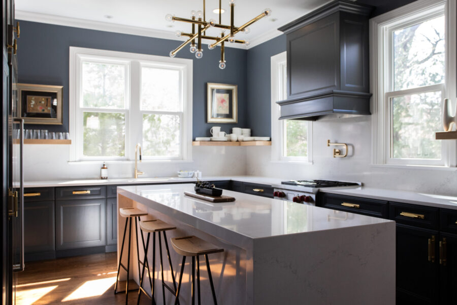 Expansive contemporary kitchen renovation includes dark cabinetry, bright counters, grand island.