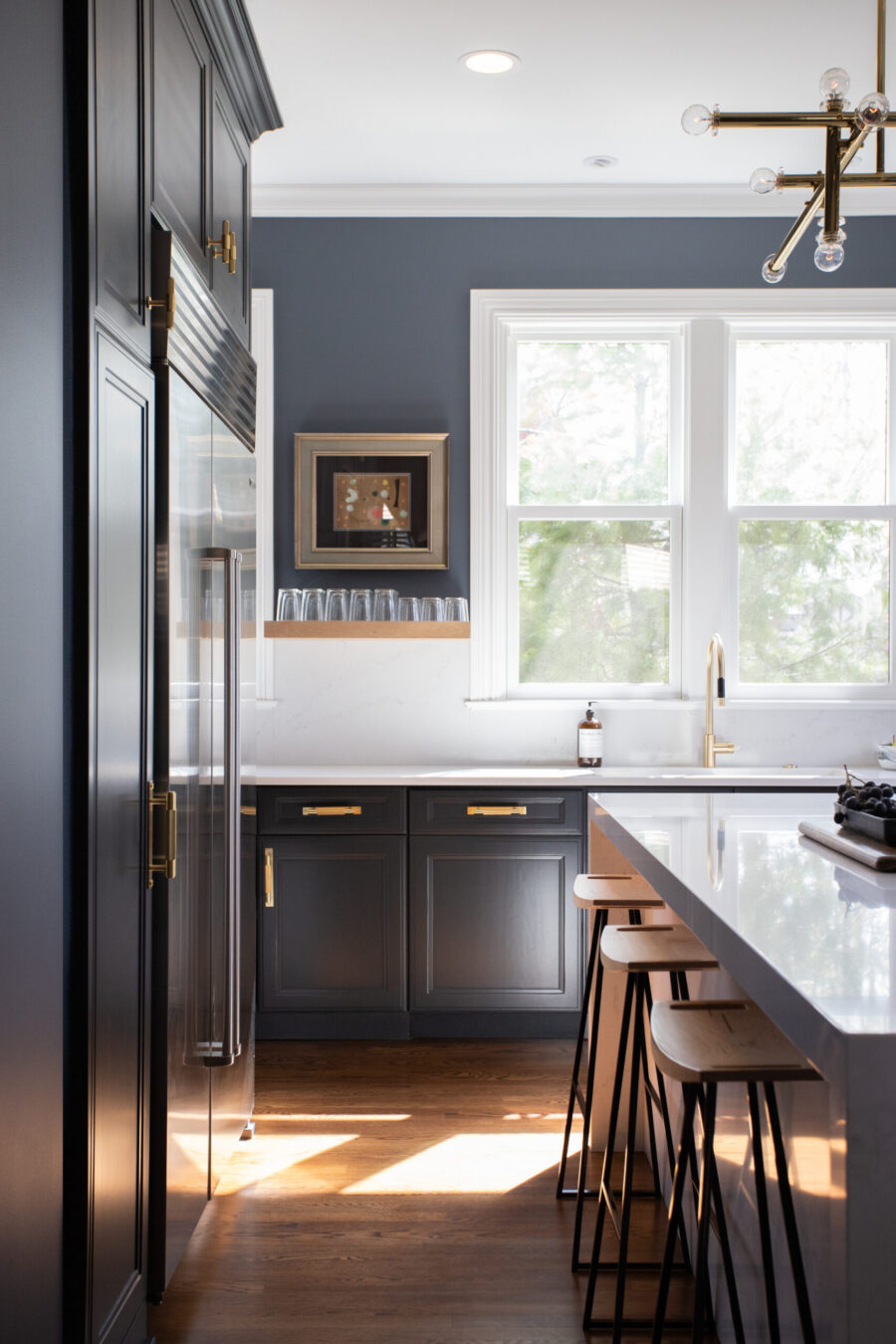 Twin Cities kitchen remodel combines dark cabinetry, white quartz, brass details, wood flooring.