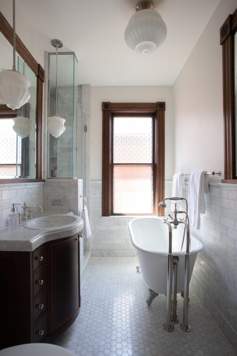 Twin Cities bathroom remodel uses marble, dark wood, bright natural light, and classic fixtures.