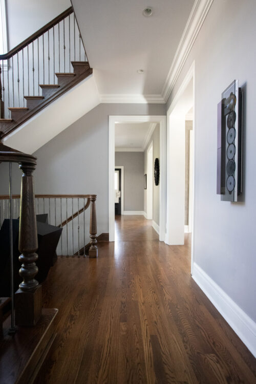 Hardwood-staircase hallway has wide-plank floors, crown-molding, recessed-lighting, metal-balusters