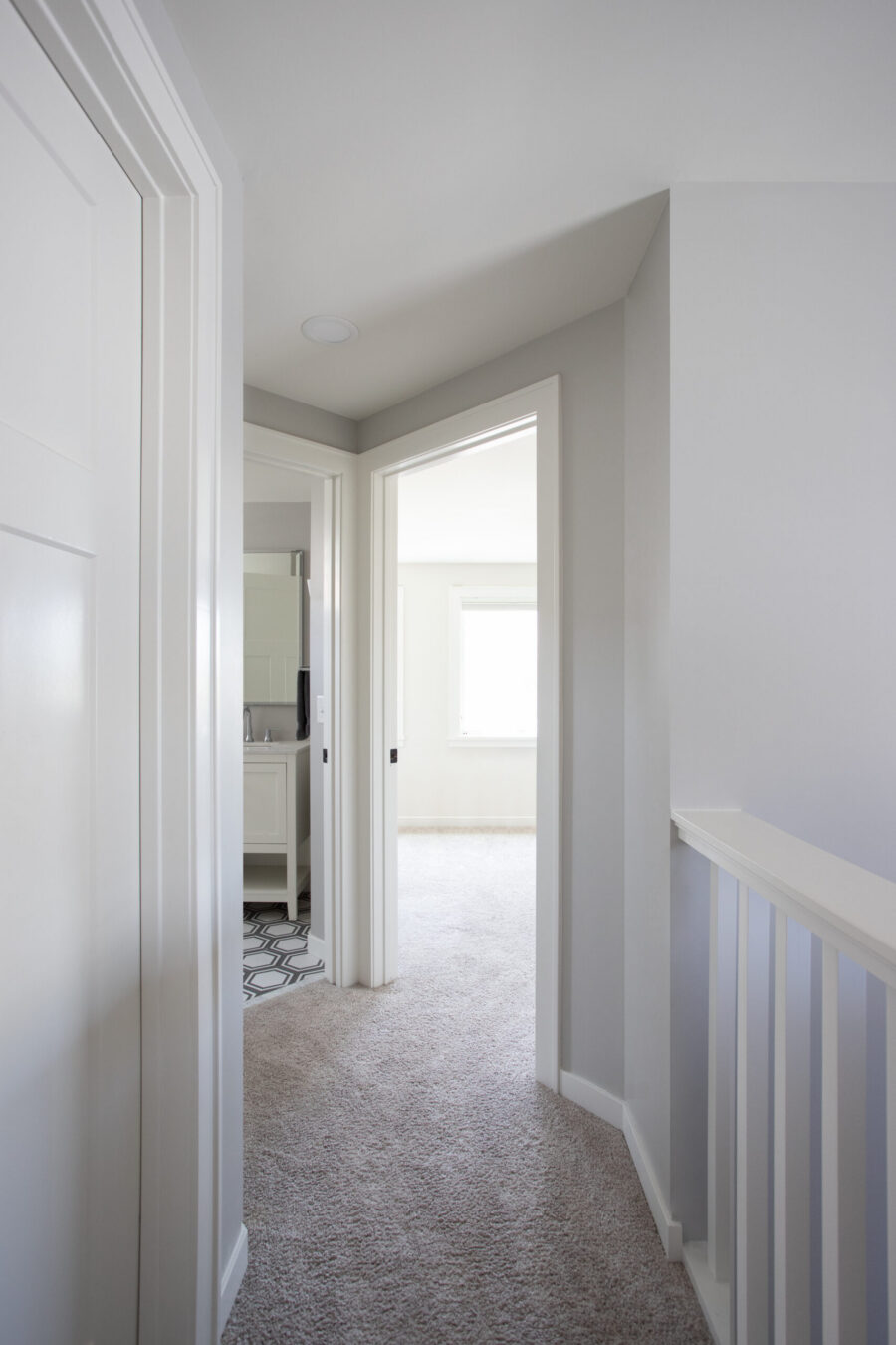 Renovated Twin Cities residential hallway, light gray walls, plush carpet, contemporary bathroom.