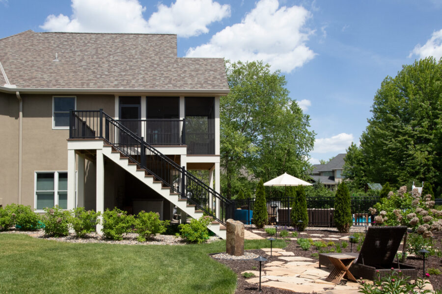 Custom design-build: stucco home, multi-level screened porch, black railings, flagstone patio, landscape lighting.