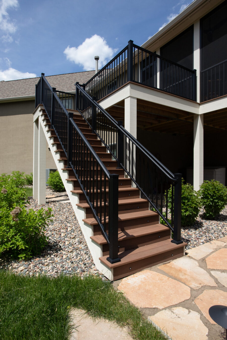 Multilevel deck remodel features composite treads, black railings, and integrated lighting.