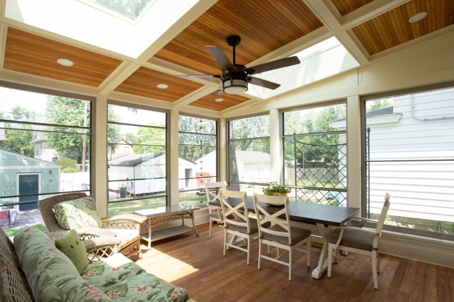 Sunroom-addition features wood-coffered ceiling, skylights, expansive windows, hardwood-flooring.