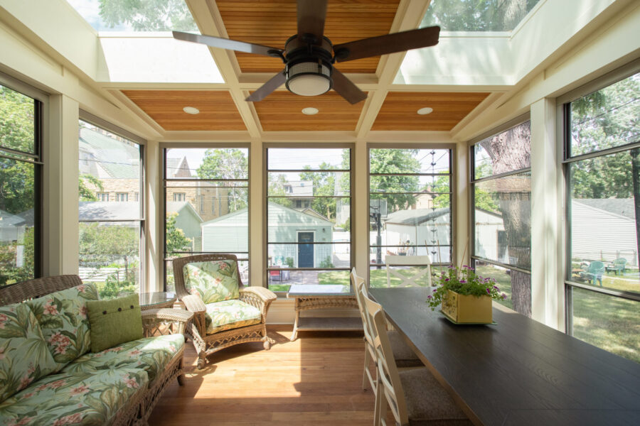 Twin Cities sunroom renovation; wood-coffered ceilings, expansive windows, wicker furniture, dining.