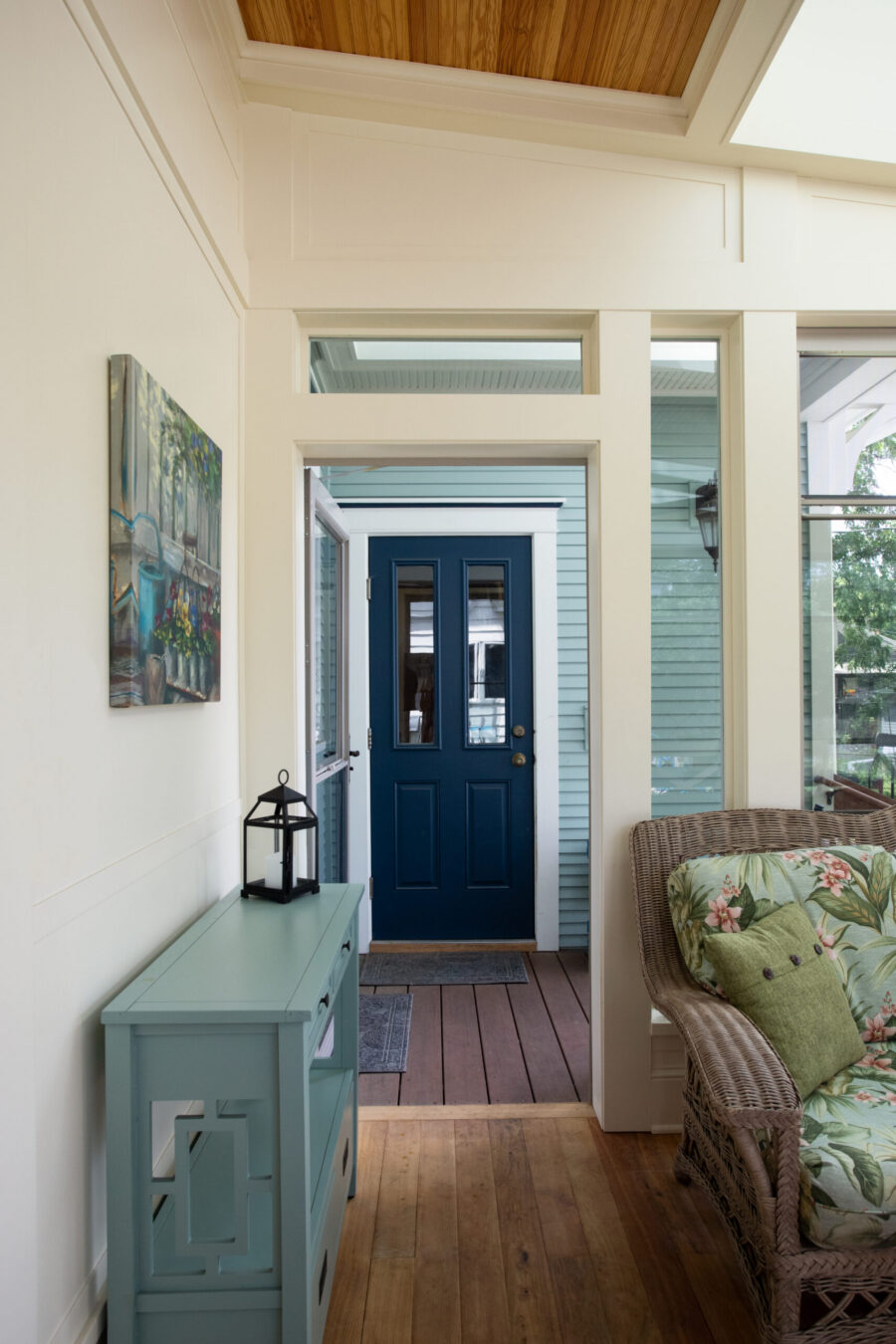 Sunroom renovation features extensive hardwood flooring, dark blue door.