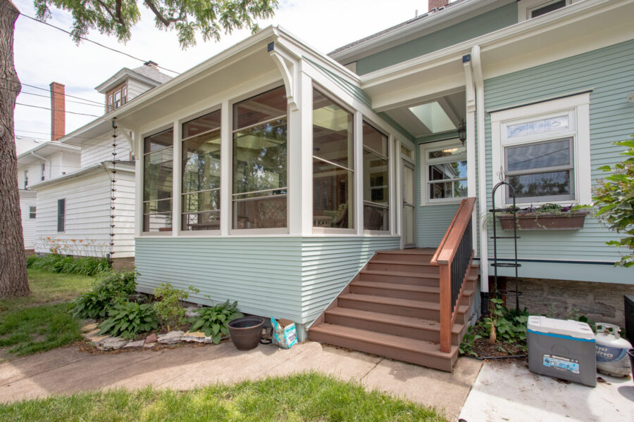 Newly renovated light blue home features bright sunroom addition, large windows, wooden steps, skylight.