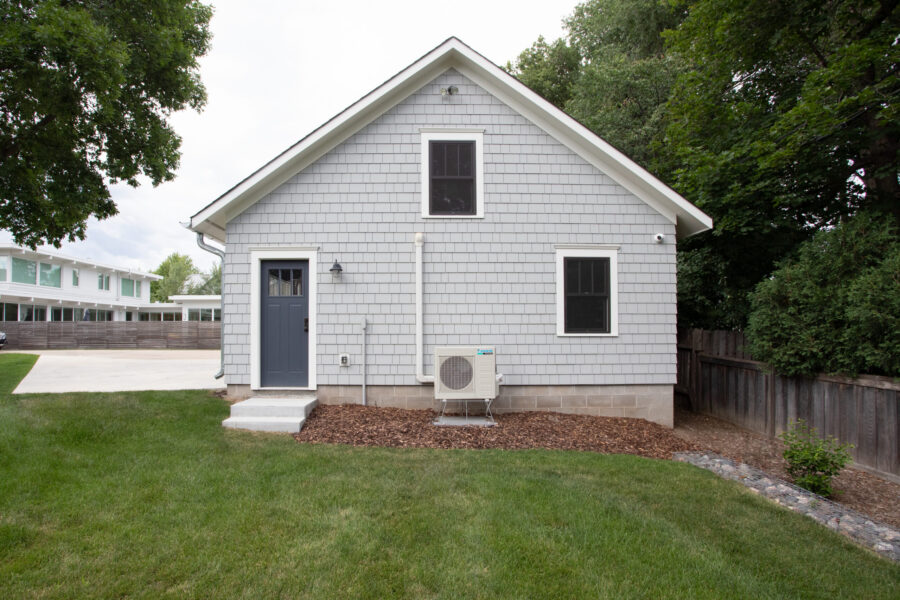 Recently renovated gray shingle exterior features dark door, windows, and new outdoor unit.