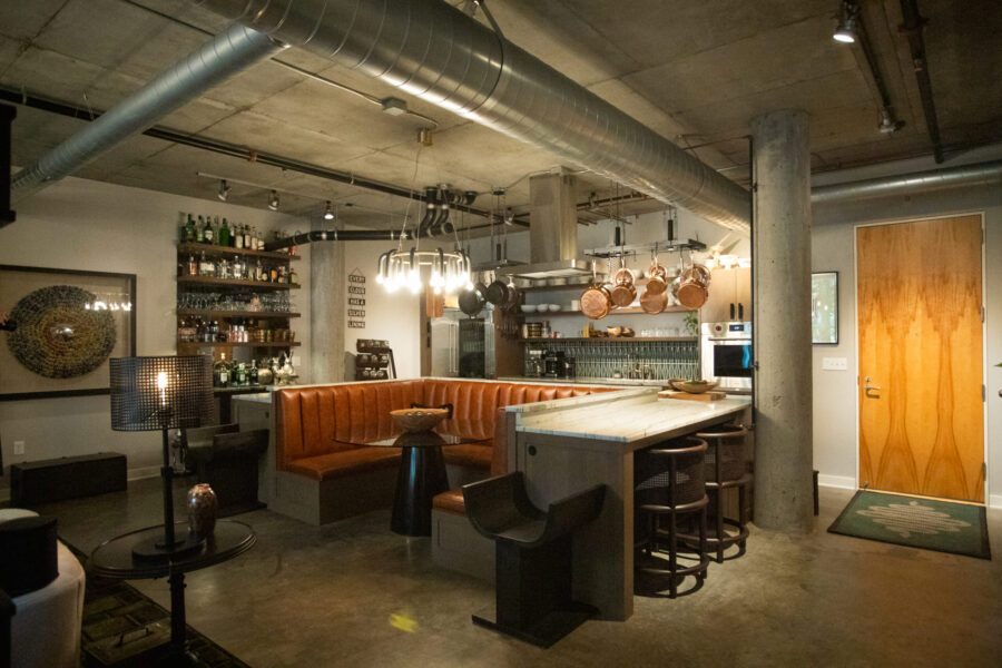 Kitchen remodel features concrete, ductwork, marble, orange leather banquette.