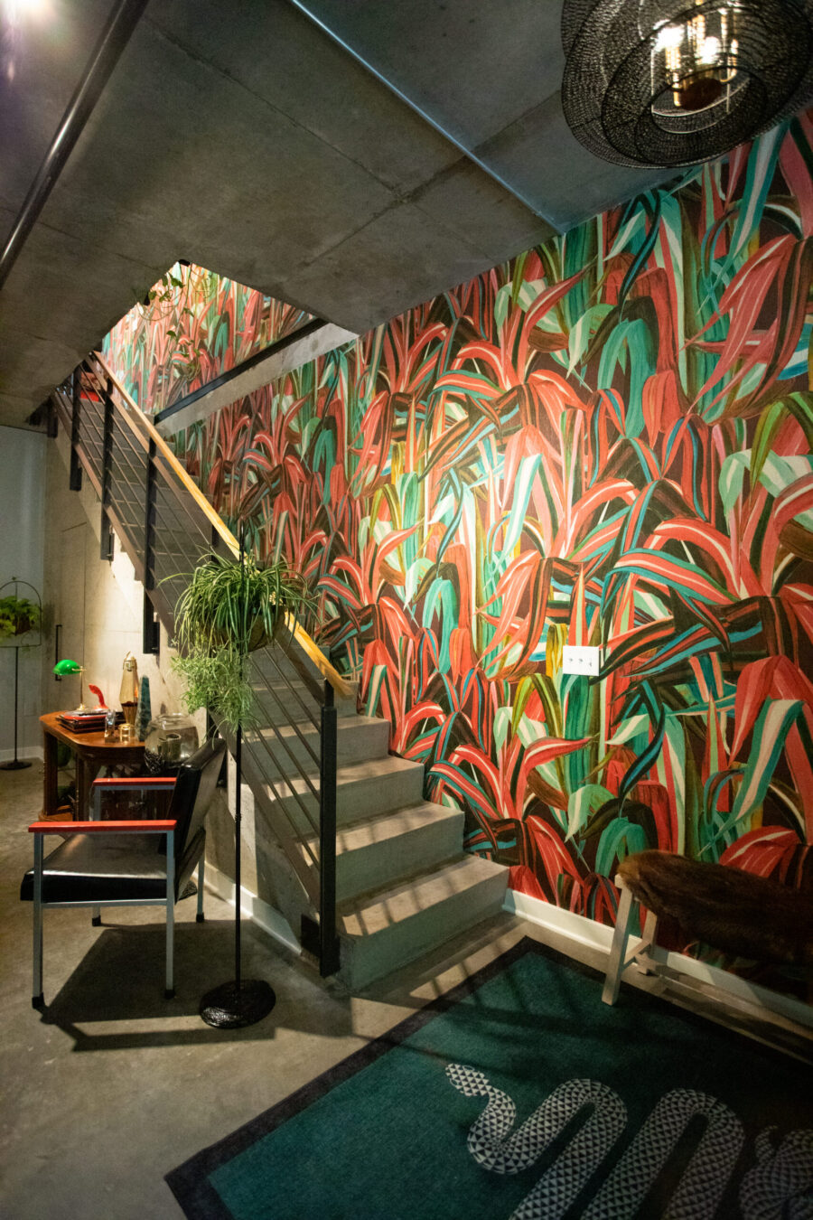 Concrete stairs ascend a wall of vibrant botanical wallpaper in this striking Twin Cities home renovation.