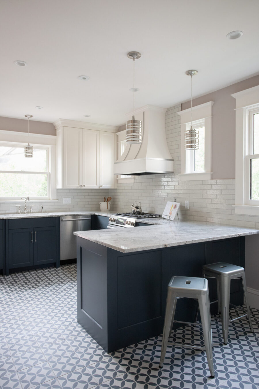Twin Cities kitchen remodel features navy base, white upper cabinets, and light marble counters. Patterned floor tile. Bright lighting.