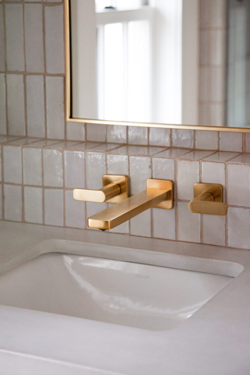 Twin Cities bathroom remodel integrates gold wall-mount faucet, white sink, textured tile.