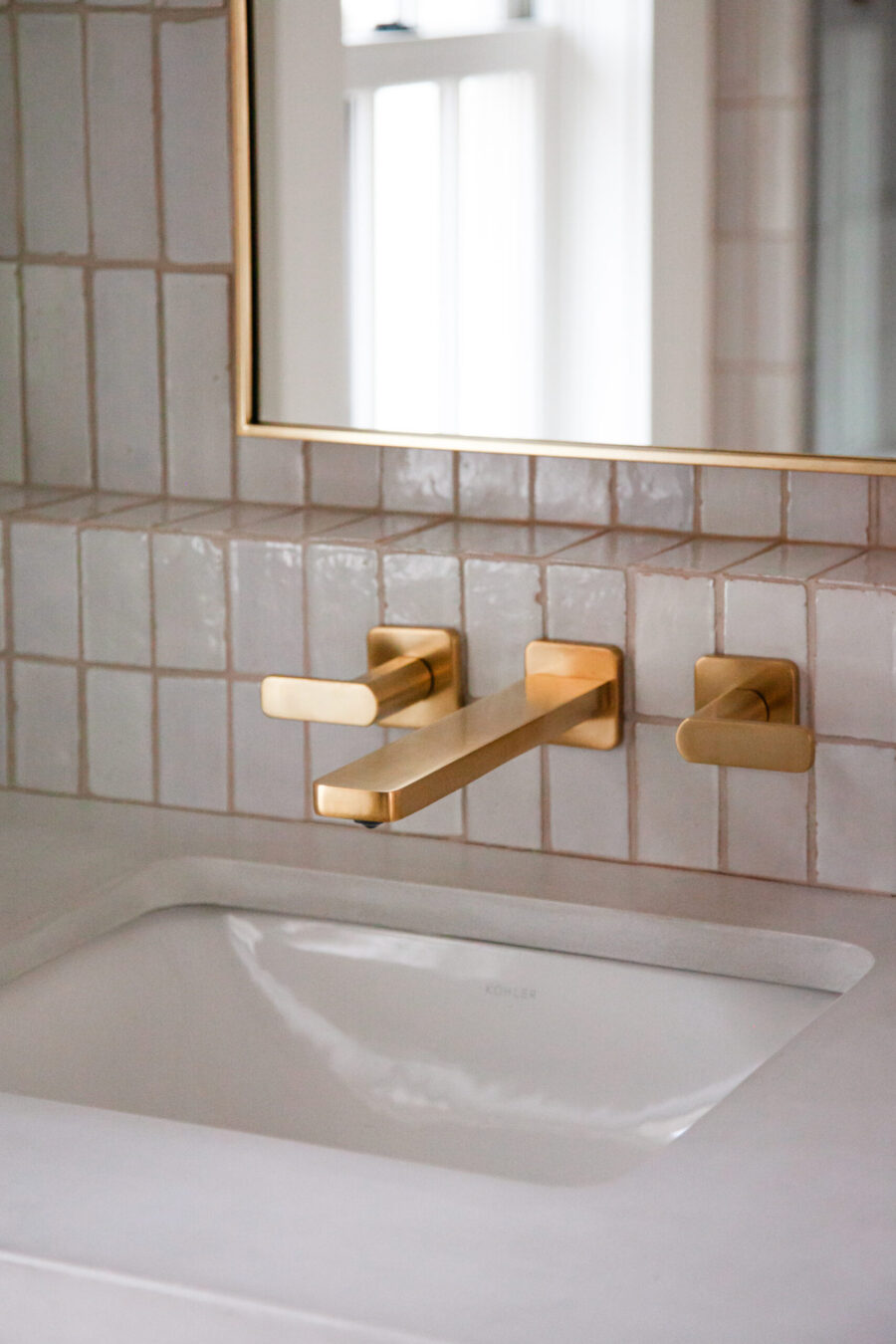 Twin Cities bathroom remodel integrates gold wall-mount faucet, white sink, textured tile.