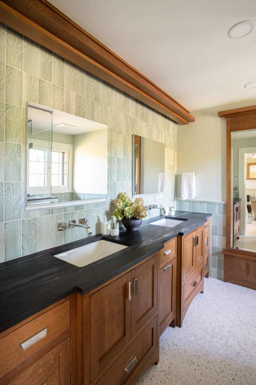 Bathroom remodel: Wood dual vanity, dark counters, green patterned tiles.