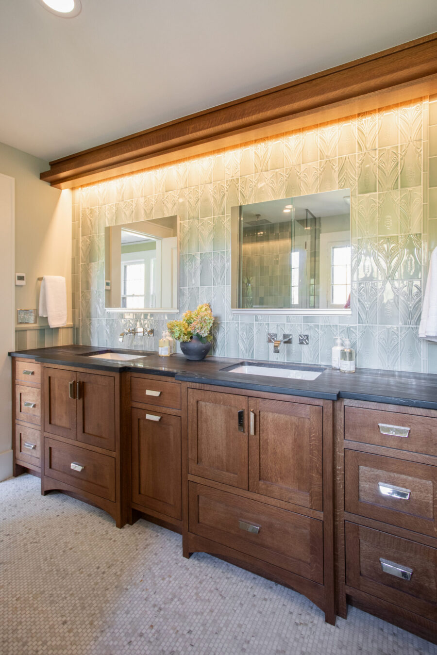 Twin Cities bathroom remodel: dark wood double vanity, green patterned tile, lit.