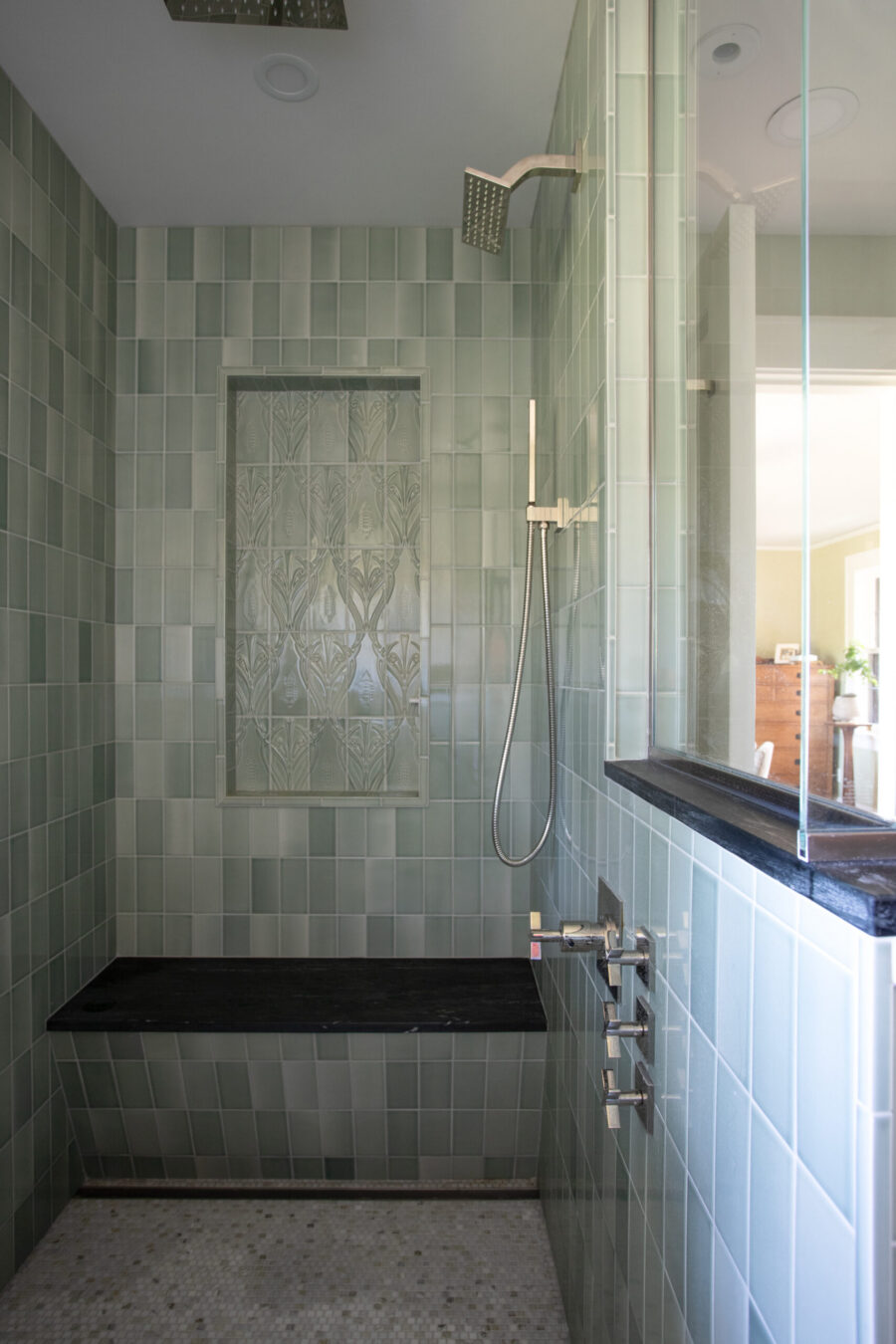 Green-tiled shower features dark bench, decorative niche, chrome hardware.