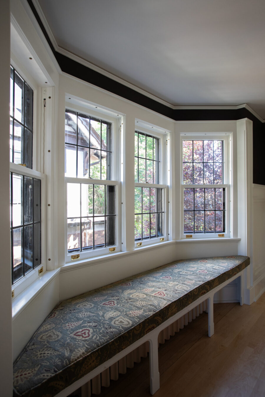 Dark-trimmed, brightly-lit, patterned-cushioned Twin Cities bay window renovation.