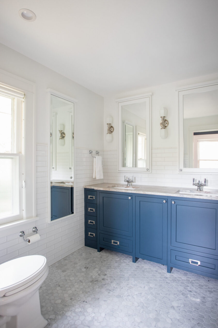 Twin Cities bathroom renovation incorporates blue double-vanity cabinetry, hexagon floor tiling.