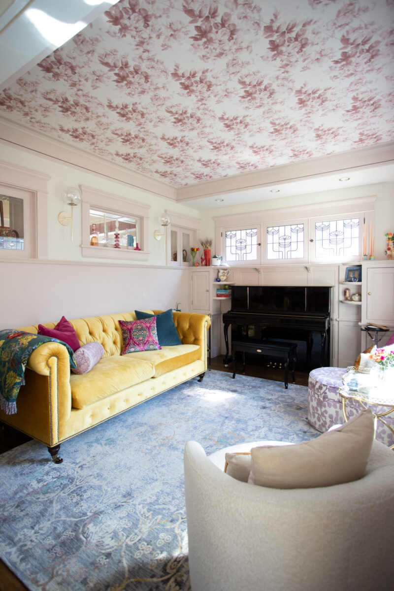 Twin Cities living room renovation displays yellow velvet sofa, floral ceiling.