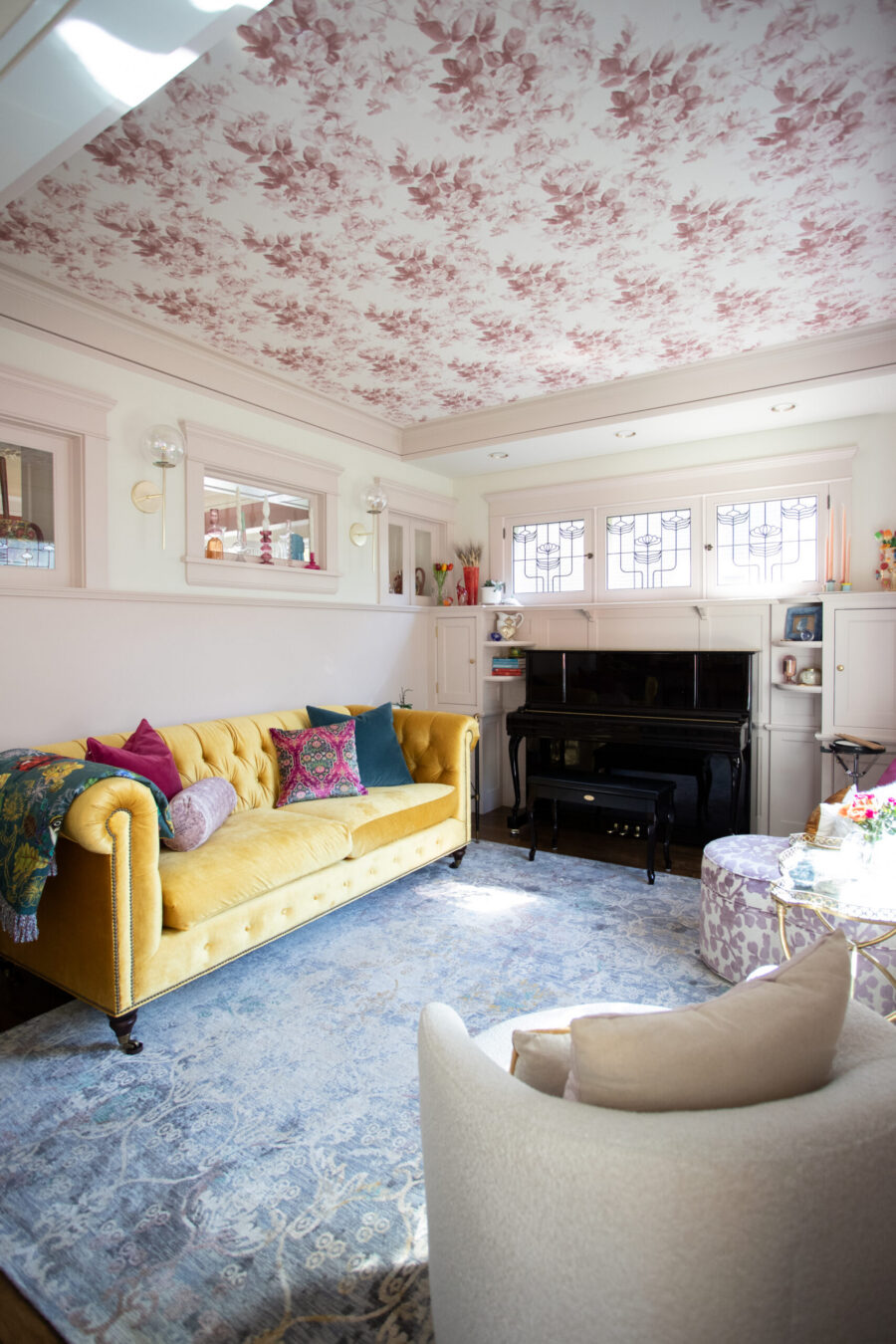 Twin Cities living room renovation displays yellow velvet sofa, floral ceiling.