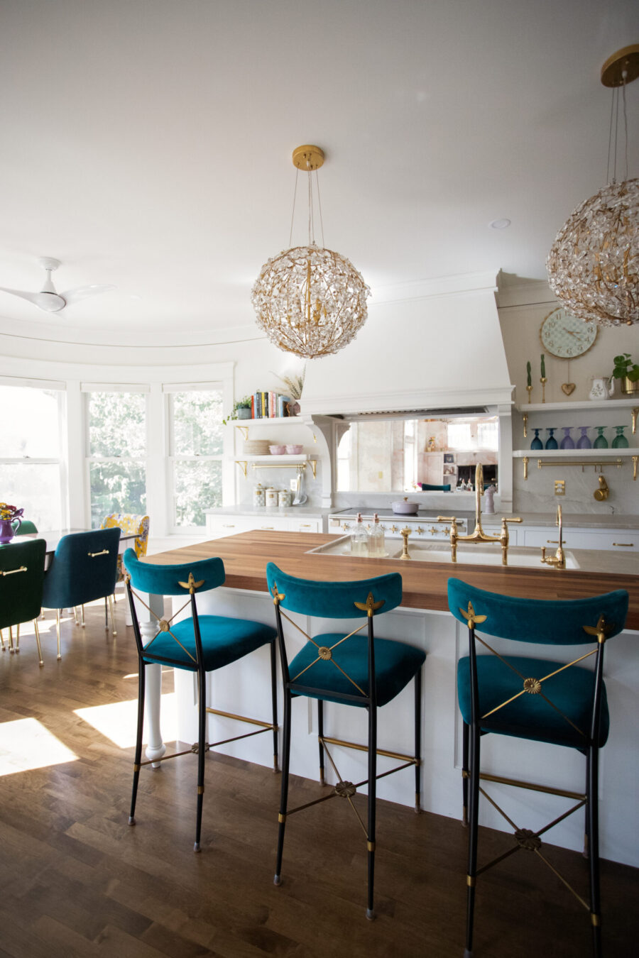Twin Cities kitchen remodel's butcher block island, teal velvet barstools, crystal chandeliers.