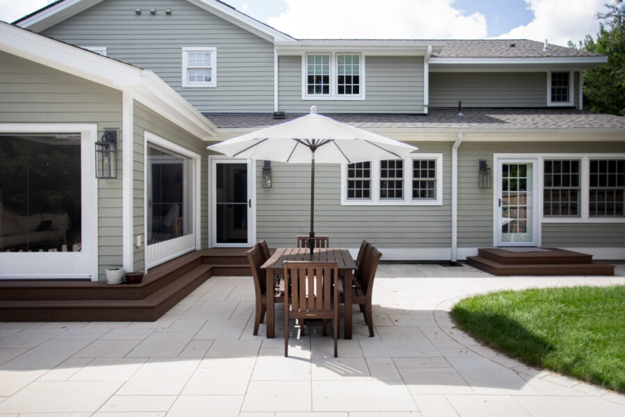 Home renovation features light green siding, paver patio, dark wooden stairs and outdoor dining.
