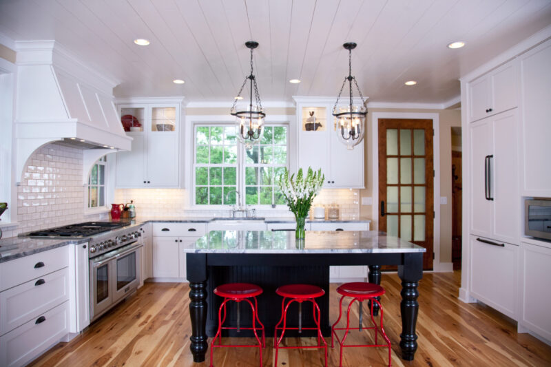 Twin Cities kitchen remodelling features white cabinetry, black island, hardwood flooring.