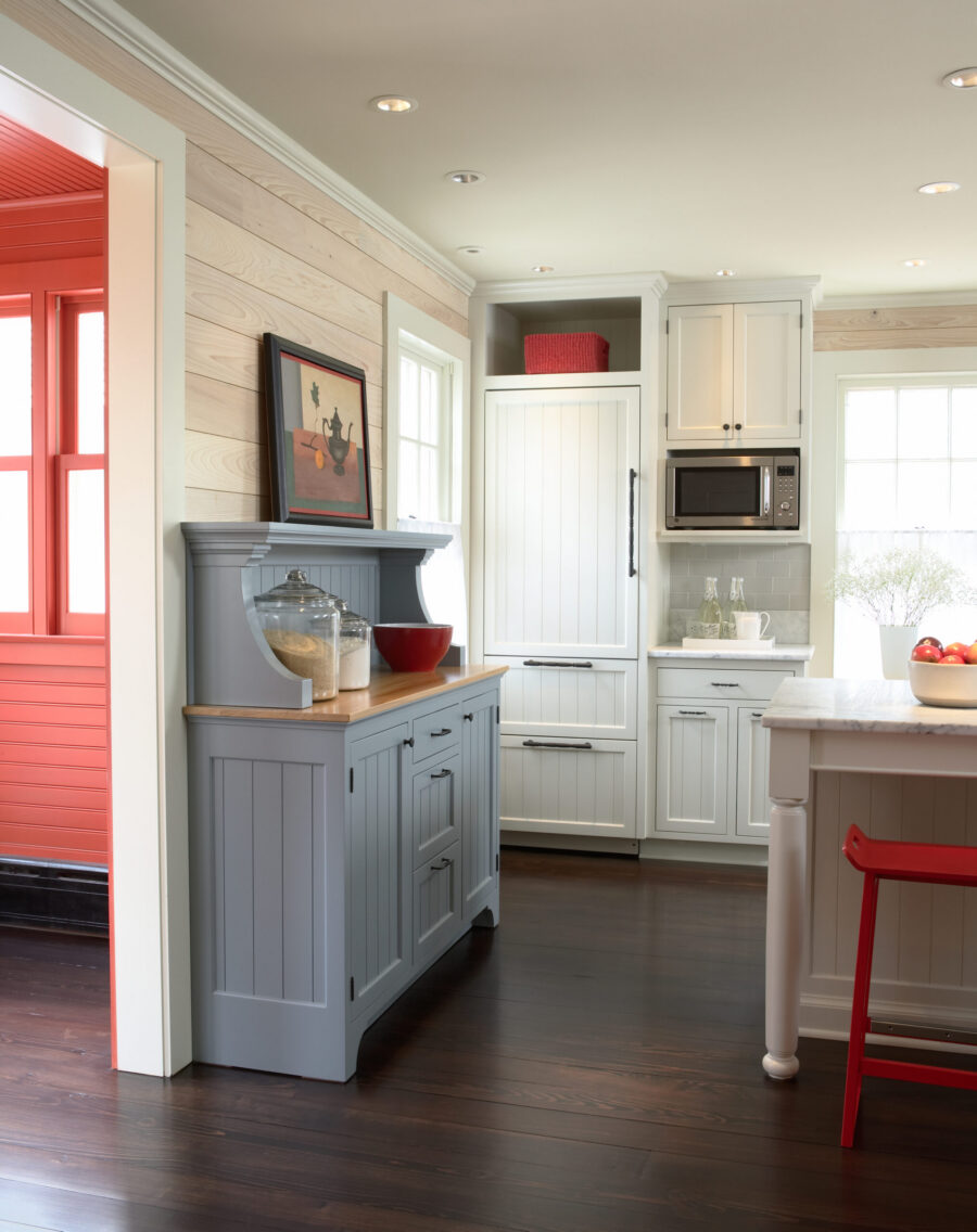 Twin Cities kitchen remodel features white cabinets, dark wood floors, a grey hutch, and bright red accents.