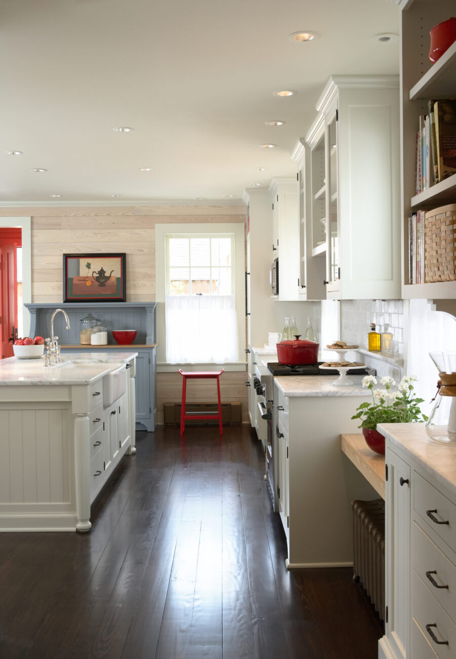 Bright kitchen remodel features white cabinetry, dark flooring, plank walls.
