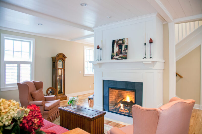 A home renovation creates a Twin Cities living room with a white fireplace, warm fire, and wood floors.