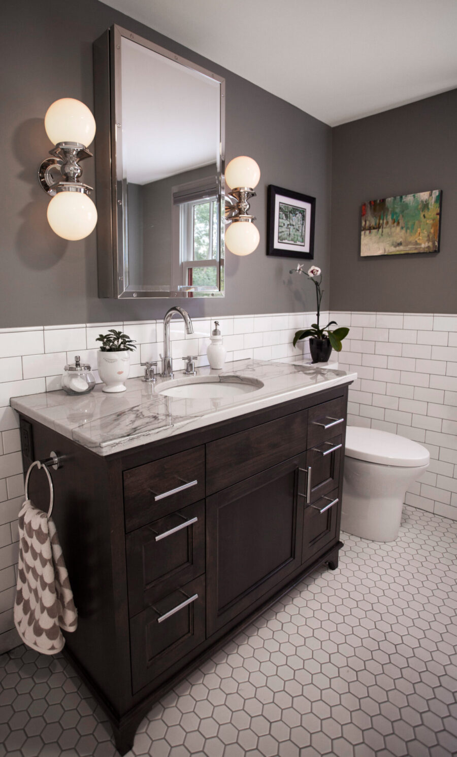 Twin Cities bathroom remodel features dark vanity, marble, chrome, and subway tile.