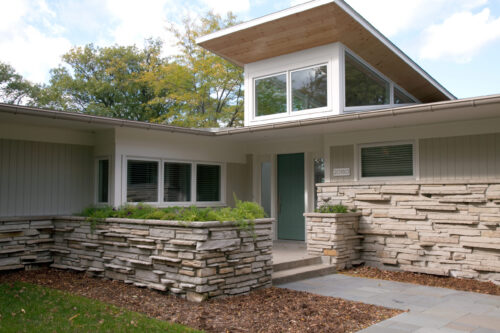 Midcentury modern house features stacked-limestone planters, horizontal-siding, clerestory windows