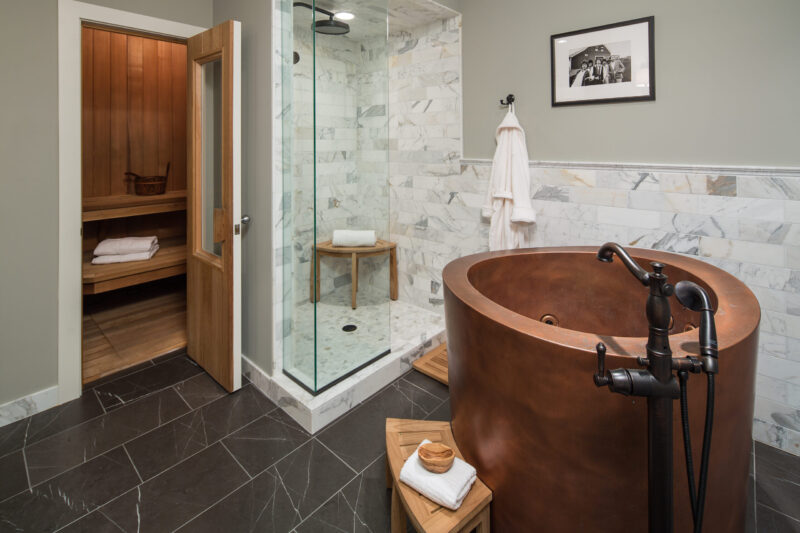 Luxurious bathroom remodel offers freestanding copper tub, marble shower; a wooden sauna.