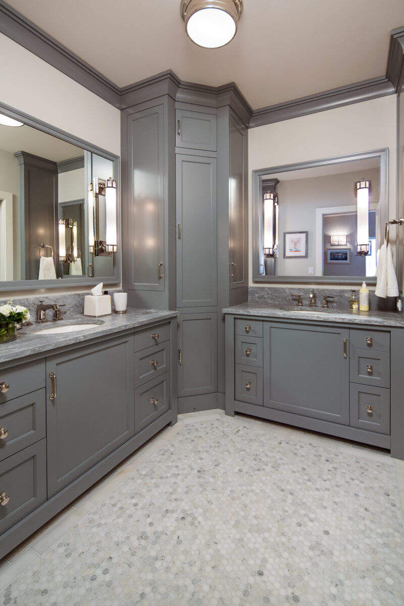 Twin Cities bathroom renovation features grey shaker vanities, marble counters, hexagon mosaic floor tiles, and bright lighting.