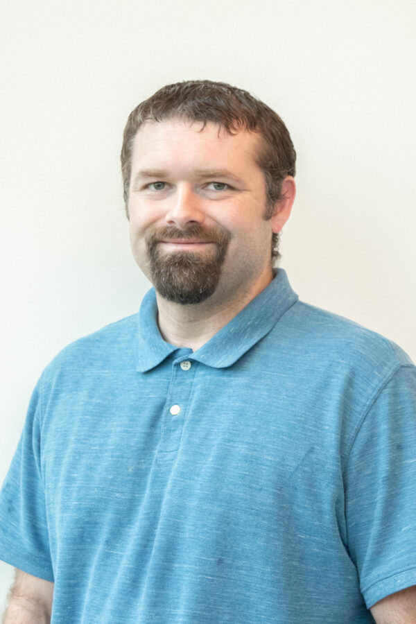 Illuminated man. Blue textured polo. Bright, unadorned studio backdrop.